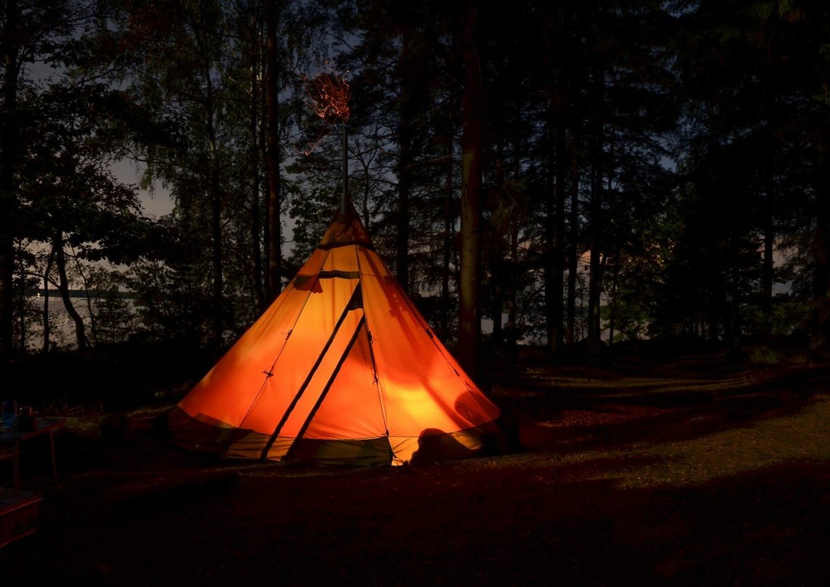 Beleuchtetes Campingzelt in einem Wald in Schweden bei Nacht